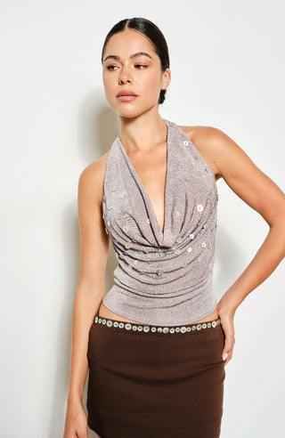 Woman wearing a gray sleeveless top with embellishments on a white background