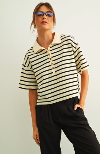 Woman wearing a striped polo shirt and sunglasses against a plain background